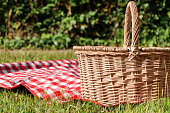 Picnic basket with checkered tablecloth on green grass outdoors, space for text