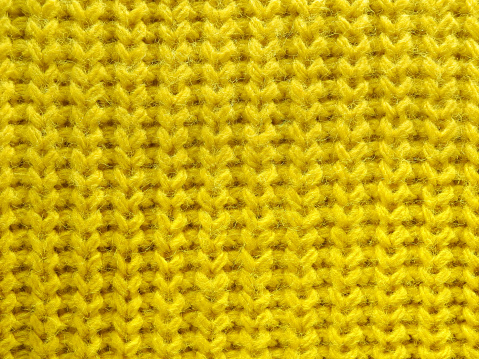 Yellow knitted wool fabric texture close-up as background