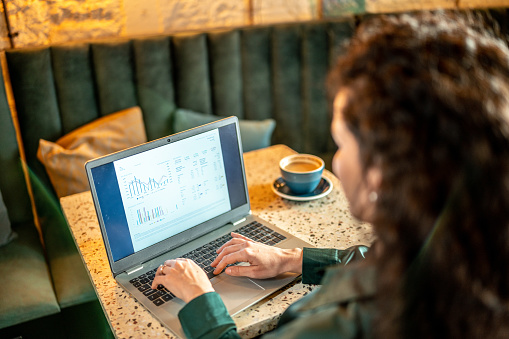 Businesswoman using laptop looking for finances at a coffee shop