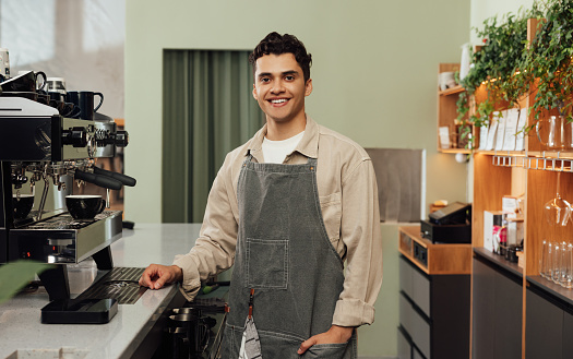 Smiling male barista in a cafe. Portrait of a cheerful man in an apron working as a barista.