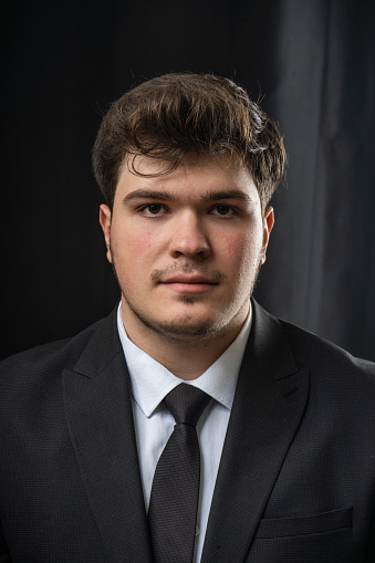 Portrait of young male in a black suit. Hero looking young man. On black background.