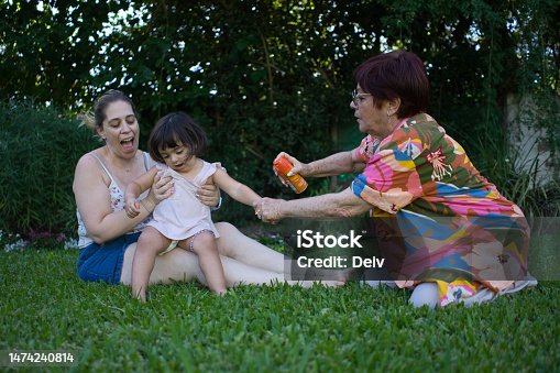 istock Grandmother putting mosquito repellent on the family. Little girl 1474240814