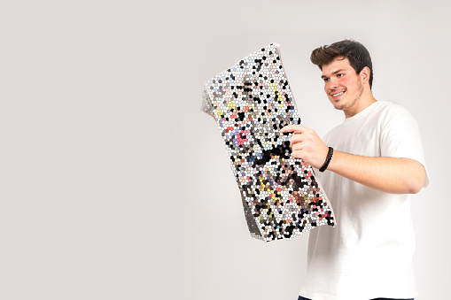 Young man reading the newspaper. Mosaiced newspaper page. A very happy facial expression. Isolated background.