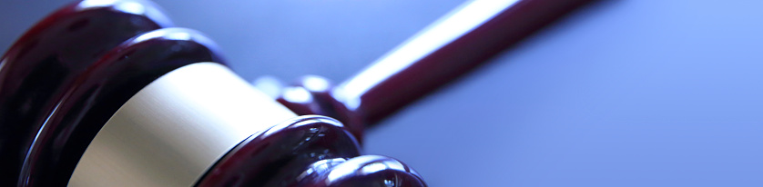 A close up of a gavel on a blue background with ample room for copy and text.