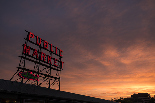 Seattle, USA - Jun 17, 2022: A vivid sunset over the neon public market sign on Pine Street at Pike Place Market.
