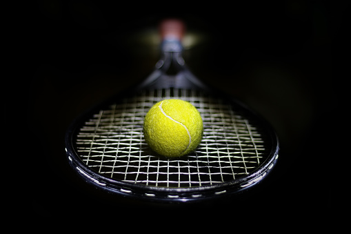 Tennis racket and tennis ball on a hardcourt.