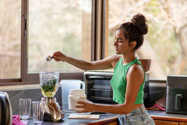 Giovane donna ispanica che taglia gli ingredienti per frullato sano in cucina - foto stock