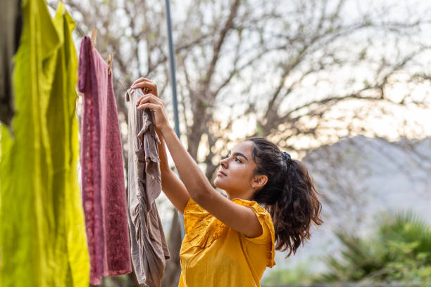 Young woman hanging clothes to dry in clothesline: sustainability concept stock photo