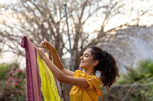 Young woman hanging clothes to dry in clothesline: sustainability concept