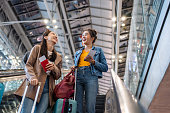 Asian young women passenger walk in airport terminal to boarding gate. Attractive beautiful female tourist friends feeling happy and excited to go travel abroad by airplane for holiday vacation trip.
