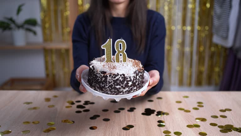 Holidays and celebration concept. Excited woman celebrating 18 birthday, blowing candle number eighteen on cake, wearing party cake and having fun on camera. Point of view or POV.