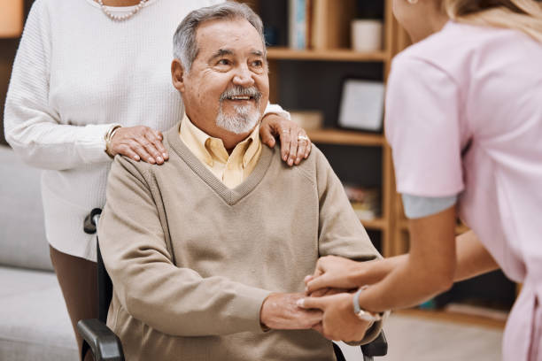 istock Disability patient holding hands with doctor for senior help, support and trust home nursing, physical therapy and healthcare. Medical worker consulting elderly man in wheelchair in caregiver welcome 1474252265