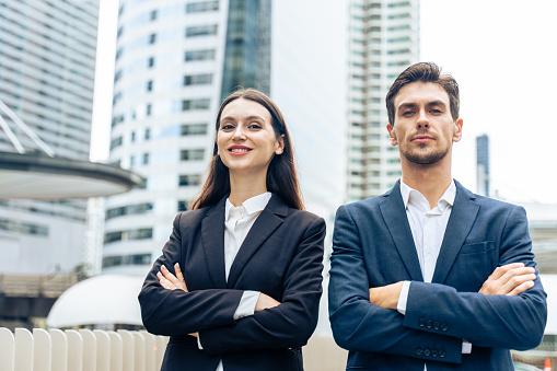 Portrait of Caucasian businessman and woman standing outdoor in city. Attractive young employee people feel happy and confident then smiling looking at camera. Job application and recruitment concept.