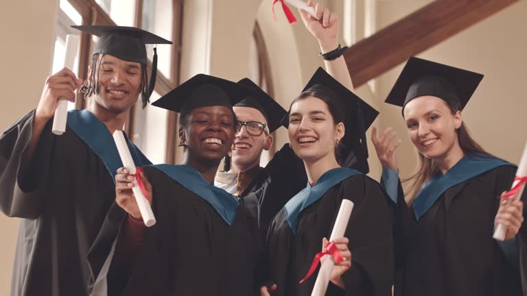 Portrait of Cheerful Graduates with Diplomas