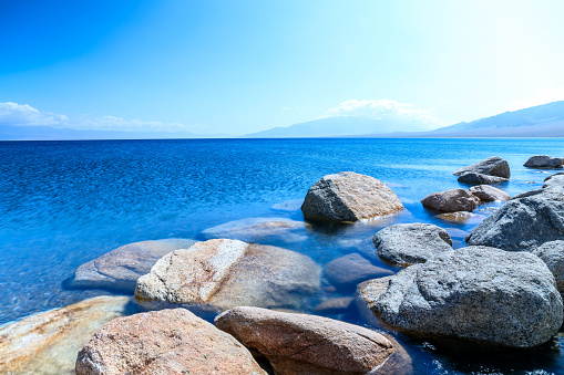 Clear lake water and rocks under blue sky.