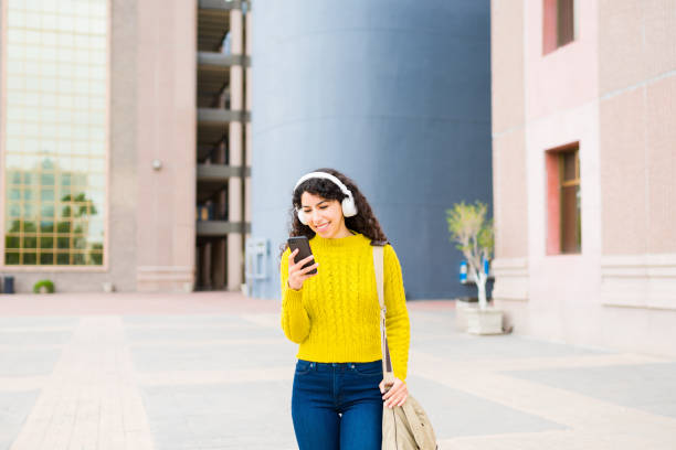 istock Beautiful woman walking on her commute to work using her smartphone 1474262462