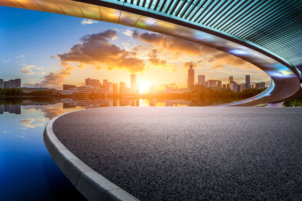 Asphalt road with city skyline at sunset