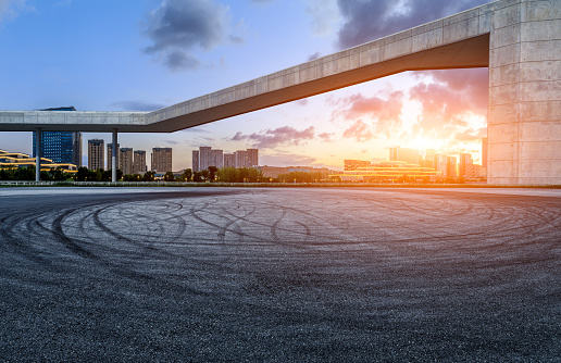 Asphalt road and city skyline with modern buildings at sunset in Ningbo, Zhejiang Province, China.