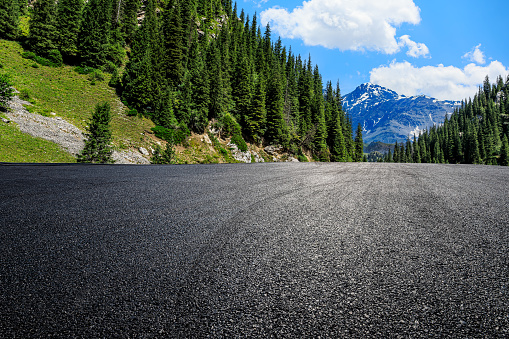 Asphalt road and green forest with mountain natural scenery in Xinjiang, China.