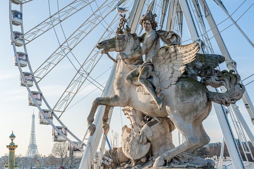 Place de la Concorde, Paris, France - Jan 8, 2018 : Perseus on Pegasus statue and Ferris wheel against blue sky