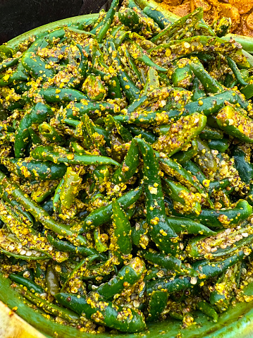 Stock photo of bucket filled with hot achar green chilli pickle at Indian market, spicy street food for sale at outdoor chutney stall / stand, elevated view of fermented condiment in India