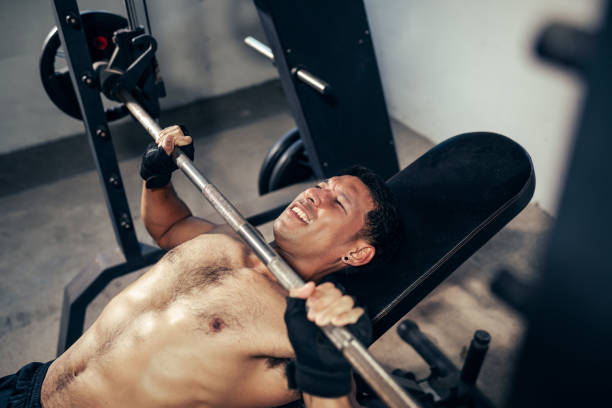 istock Fitness man exhausted expression on face workout weight training bench press with Barbell lifting in fitness gym. 1474268294