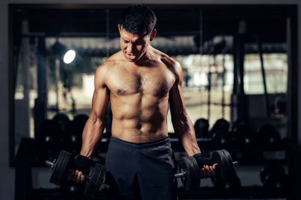 피트니스 남자는 피트니스 체육관에서 아령으로 얼굴 운동 웨이트 트레이닝 팔뚝 근육에 표정을 짓습니다. - body building weight training men flexing muscles 뉴스 사진 이미지