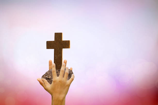 istock Human hand holding cross on blurred nature background. 1474269125