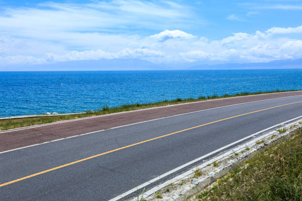 Asphalt road and lake with mountain natural scenery in Xinjiang, China.