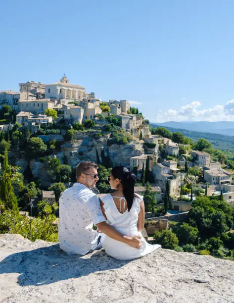 A couple of men and women on vacation in Southern France looking out over the old historical village of Gordes Luberon Provence