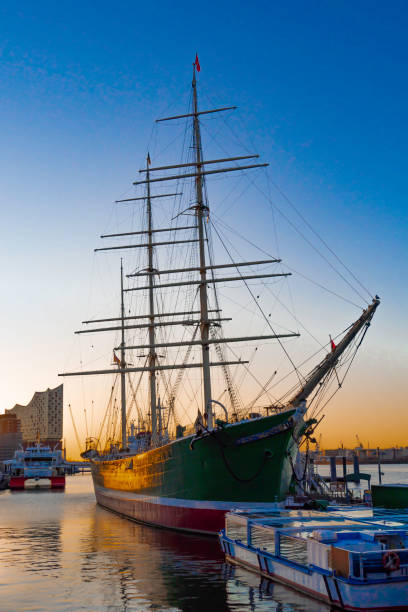 View from the north-west of a museum ship in Hamburg during sunrise, excursion boats and the Elbphilharmonie in the picture, vertical
