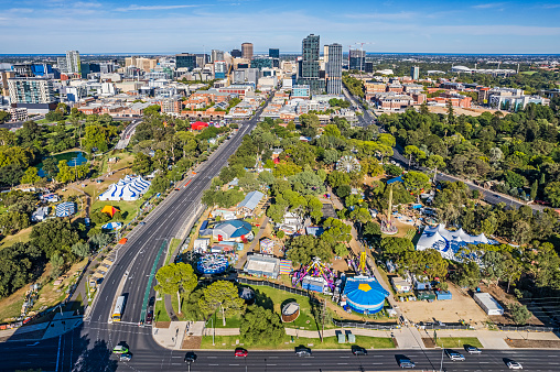 Adelaide, Australia - March 13, 2023: Aerial view city of Adelaide Eastside and CBD in morning with Fringe festival venues in the public parkland in Kaurna Country (indigenous land):  in the foreground Rundle Park/Kadlitpina with individual entertainment venues, food & drink stalls, carnival rides & stalls; to the left, Rymill Park/Murlawirrapurka; Rundle Road in foreground leading to shopping precinct in CBD; and background right is Adelaide Oval and in the distance, the ocean. Note: event activities staged in public parks with free admission to the parks precinct.