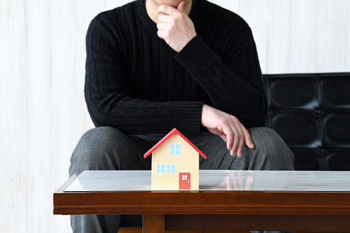 House object and thinking man in living room