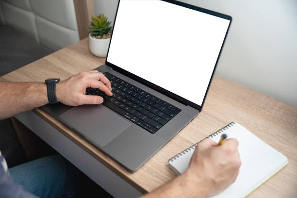 istock Unrecognisable man using a laptop with blank white screen at home, close-up shot 1474284773
