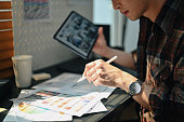 Interior designer holding digital tablet working at project, choosing color for interior at workstation.