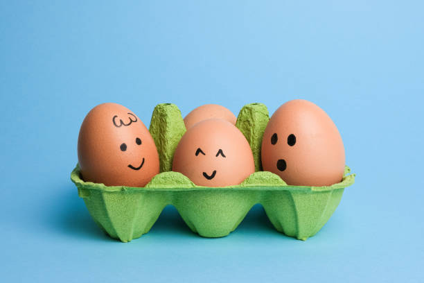 istock Cute easter eggs with funny faces in green box isolated on light blue background. Happy easter concept 1474296196