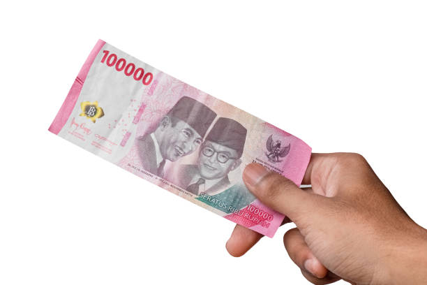 istock hand holding IDR 100,000 rupiah note isolated on white background. 1474297707