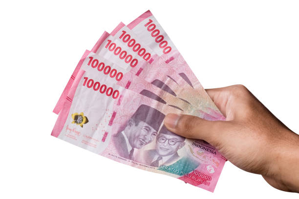 istock hand holding IDR 100,000 rupiah note isolated on white background. 1474297709