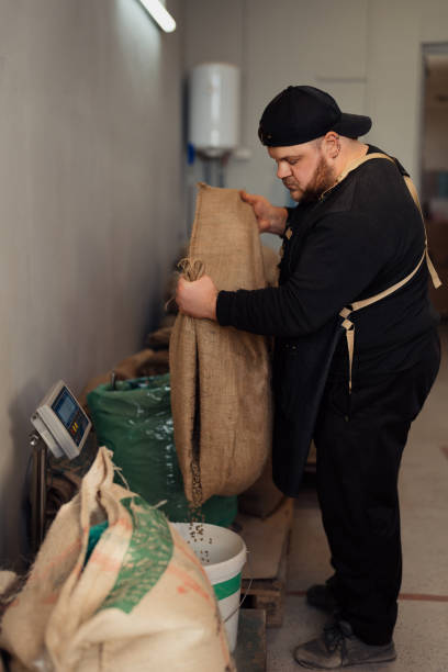 istock Man pouring coffee beans into basket from sack 1474298805
