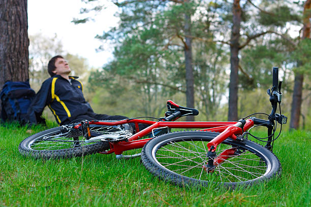 istock Red bike lying on grass. Cyclist relaxes in the background 147430161