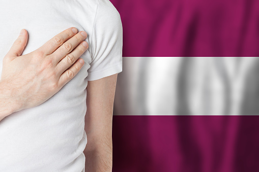 Latvian person with hand on heart on the background of Latvia flag. Patriotism, country, national, pride concept