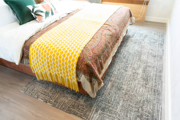 istock Bed with yellow throw blanket and grey rug in bedroom. 1474304290
