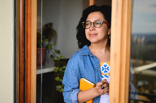 close up portrait of multiracial person in eyeglasses looking throw the window door at home and enjoying the morning.