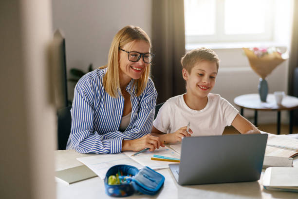 istock Female babysitter is teaching little boy use laptop application during studying 1474308261