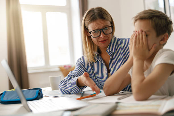 istock Serious mother try to help her son to do difficult task exercise. Education at home 1474308473