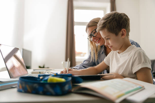 istock Happy mom and son doing homework and studying with laptop together. Home education 1474309542