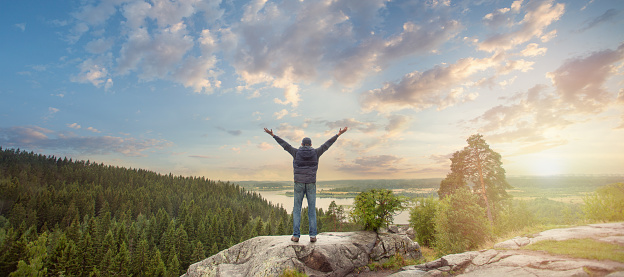 Man looking at the beautiful view of sunrise with arms outstretched on mountain top