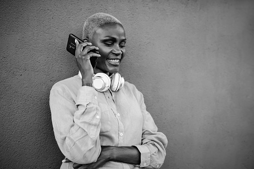 Happy smiling African woman doing a call with mobile smartphone outdoor - Black and white editing