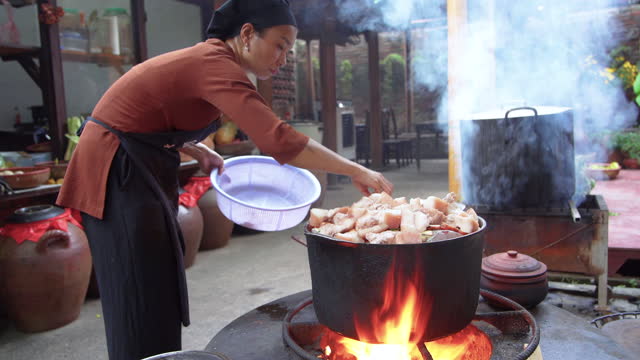 young vietnamese woman cooking steamed fish on open fire in restaurant
