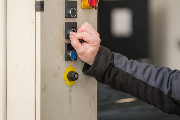 istock Selective focus. Detailed view of an arm and hand from a blue-collar working pushing on a button from a hydrolic car lift with a black car in the background. car service, repair, maintenance concept. 1474315850
